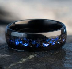 a black and blue ring with stars in the center on top of a stone surface