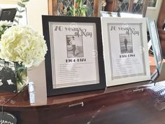 two framed pictures sitting on top of a wooden table next to a vase with flowers