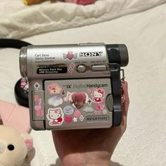 a person is holding up a camera with hello kitty stickers on it's side