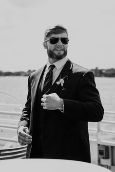 a man in a suit and sunglasses on a boat