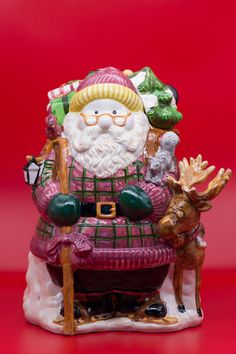 a santa clause figurine sitting on top of a chair with reindeers around it