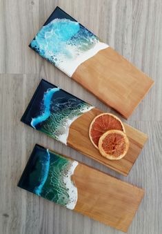 three wooden trays with orange slices on them and an ocean scene in the background