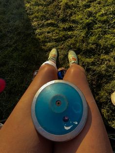 a person sitting in the grass with their legs crossed and holding a frisbee