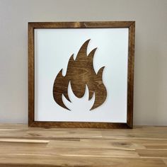 a wooden frame with a fire symbol cut out of it sitting on a wood table