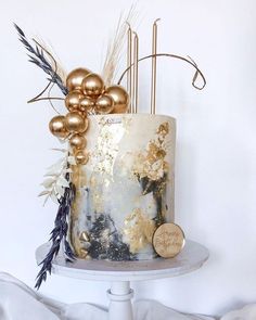 a white cake with gold decorations and some feathers on it's side, sitting on top of a table