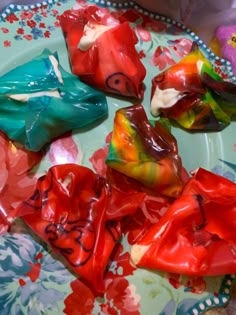 colorful candies sitting on top of a blue and green plate with flowers around them