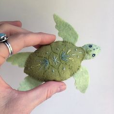 a hand holding a green felt sea turtle ornament