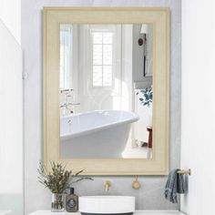 a bathroom sink sitting under a mirror next to a bath tub in a white room