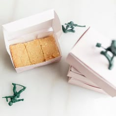 a box with some food inside of it next to two small figurines on the table