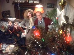 an older man and two young children sitting in front of a christmas tree