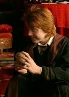 a young man sitting on a red chair holding a piece of bread in his hands