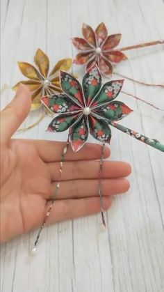 a person is holding some paper flowers in their hand and it looks like they have been made out of leaves