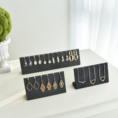 several pairs of earrings are on display in front of a vase with a green plant