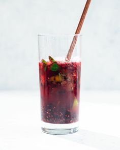 a glass filled with liquid sitting on top of a white table next to a wooden stick