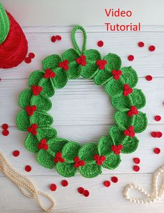 a crocheted christmas wreath with red and green poinsettis next to it