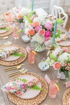 the table is set with pink and white flowers, gold place settings, and candles