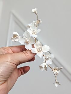 a hand holding a white flower head piece