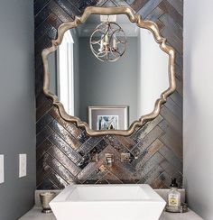 a white sink sitting under a bathroom mirror next to a wall mounted faucet