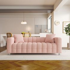 a pink couch sitting on top of a hard wood floor next to a white rug