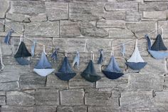 several blue and white umbrellas hanging from a string on a stone wall with grey bricks