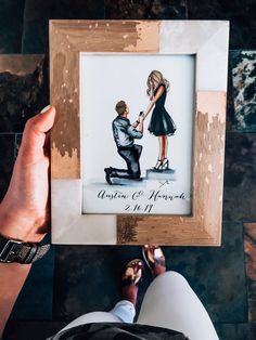 a person holding up a drawing of a man kneeling down with a woman's foot on the ground