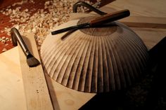 a wooden table topped with lots of wood shavings next to a piece of plywood