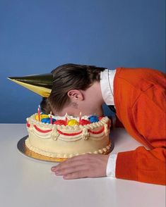 a young man leaning over a cake with candles on it's face and his head sticking out from under the cake