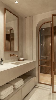 a bathroom with two sinks, mirrors and towels on the counter top in front of an open shower door