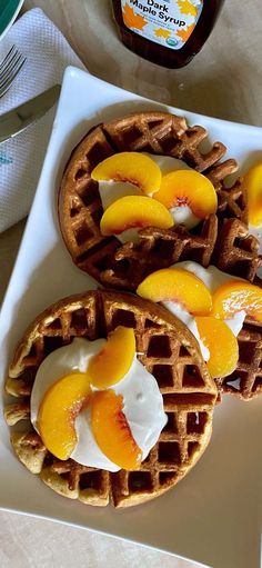 three waffles on a white plate topped with peaches and yogurt