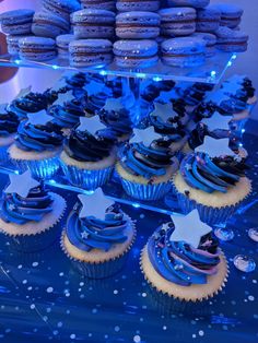 blue cupcakes with stars on them are displayed in front of other pastries