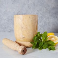 a wooden mortar, lemon and mint on a white counter with grey background in the foreground