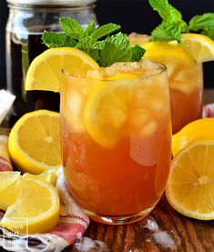 two glasses filled with lemonade and mint garnish on a table next to sliced lemons