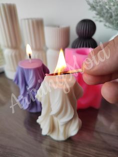 a person lighting a candle on top of a wooden table next to other small candles