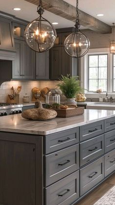 a large kitchen with gray cabinets and lights hanging from it's ceiling over the island