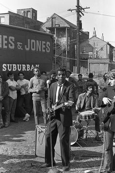 a group of people standing around each other in front of a building with a band on it