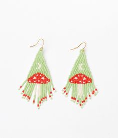 a pair of green and white beaded earrings with red mushrooms on the bottom, hanging from