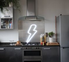 a kitchen with stainless steel appliances and a neon sign on the wall above the stove