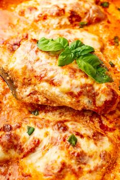 two pieces of pizza with cheese and basil on top are being held by a fork