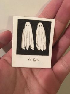 a person holding up a small magnet with two ghost figures on it's side