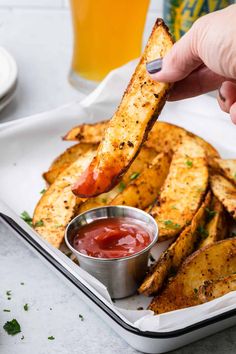 a person dipping ketchup on some french fries