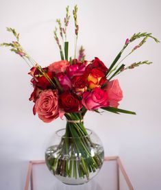 a glass vase filled with red and pink flowers