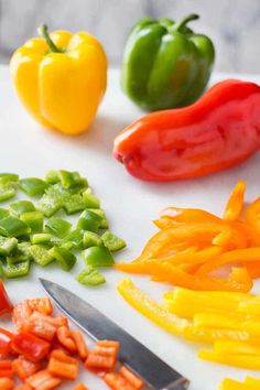 several different colored peppers on a cutting board with a knife and some diced up carrots