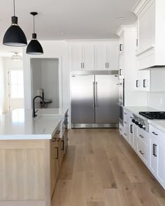 a large kitchen with white cabinets and stainless steel appliances, along with wood flooring