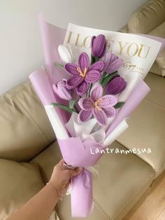 a person holding a bouquet of flowers on top of a couch next to a pillow