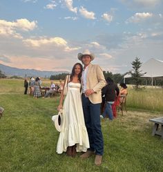 a man and woman standing next to each other in the grass at an outdoor event