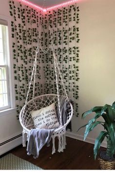 a white hanging chair next to a potted plant