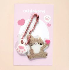 a card with a cat holding a heart and a bead necklace attached to it