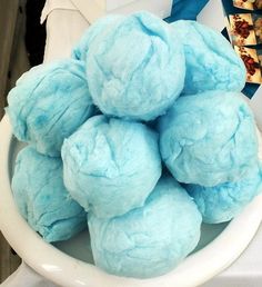 a white bowl filled with blue colored balls of doughnuts on top of a table