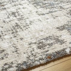 a white rug with blue and gray designs on the bottom is laying on a wooden floor