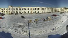 an aerial view of a large building and construction site in the background, with snow on the ground